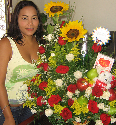 A Colombian woman receiving beautiful flowers, fruits, chocolate, teddy bear and wine as a gift