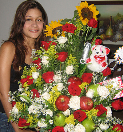 A Colombian woman receiving beautiful flowers, fruits, chocolate, teddy bear and wine as a gift