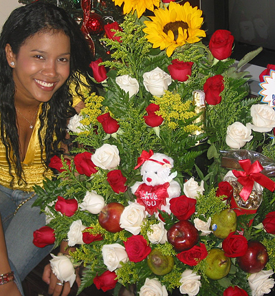 A Colombian woman receiving beautiful flowers, fruits, chocolate, teddy bear and wine as a gift