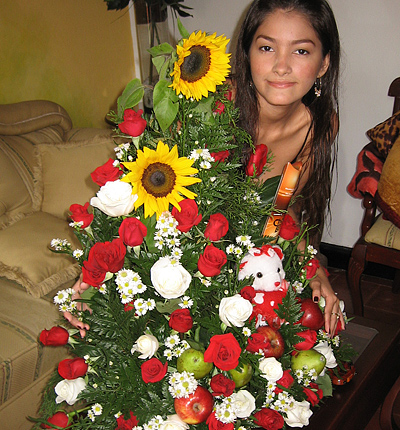 A Colombian woman receiving beautiful flowers, fruits, chocolate, teddy bear and wine as a gift