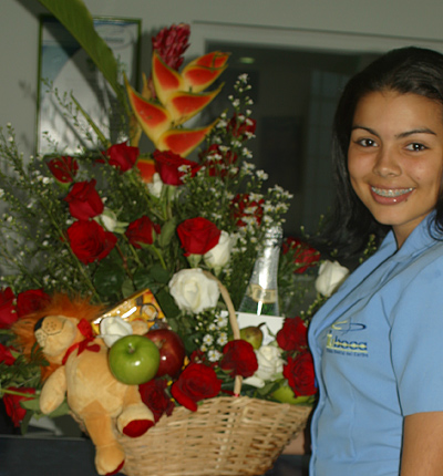 A Colombian woman receiving beautiful flowers, fruits, chocolate, teddy bear and wine as a gift