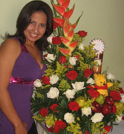 A Colombian woman receiving beautiful flowers, fruits, chocolate, teddy bear and wine as a gift