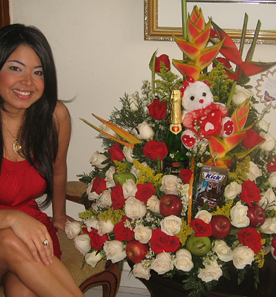 A Colombian woman receiving beautiful flowers, fruits, chocolate, teddy bear and wine as a gift