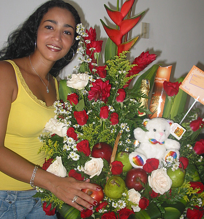 A Colombian woman receiving beautiful flowers, fruits, chocolate, teddy bear and wine as a gift