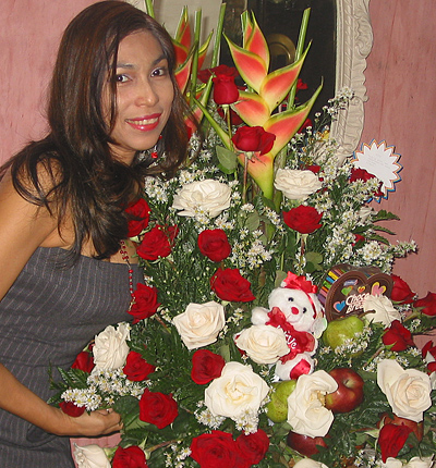 A Colombian woman receiving beautiful flowers, fruits, chocolate, teddy bear and wine as a gift