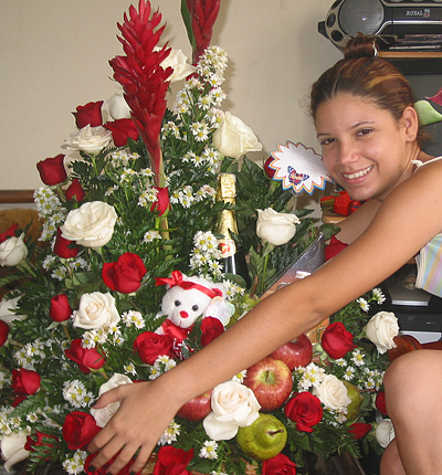 A Colombian woman receiving beautiful flowers, fruits, chocolate, teddy bear and wine as a gift