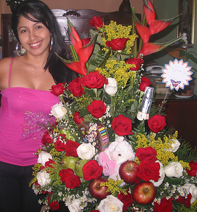 A Colombian woman receiving beautiful flowers, fruits, chocolate, teddy bear and wine as a gift