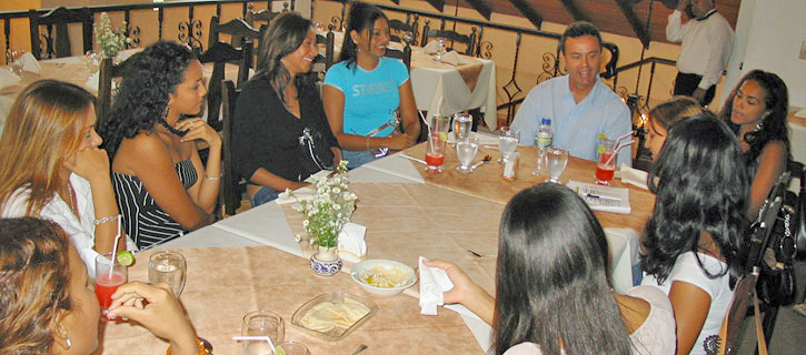 Group Introduction Gathering With Latina Women Group of Latina women sitting around a restaurant table, smiling and talking with a man in a relaxed social introduction environment