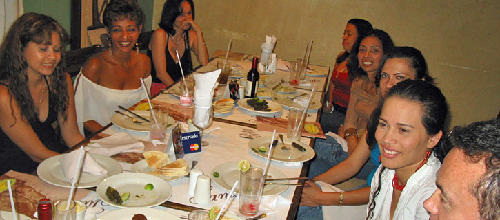 Dinner Introduction With Latina Women Group of Latina women seated around a dinner table, sharing conversation and drinks with a man during a warm and friendly introduction event
