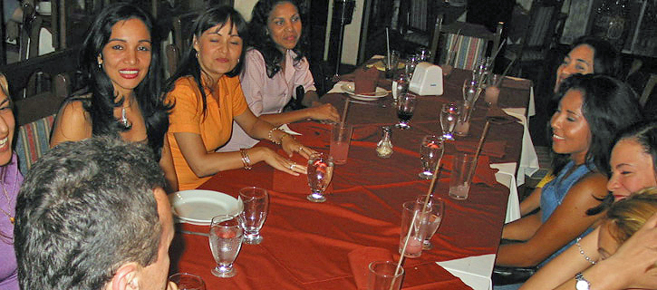 Large Group Introduction Dinner With Latina Women Group of Latina women seated around a long dinner table, smiling and conversing during a lively social introduction gathering with one man present