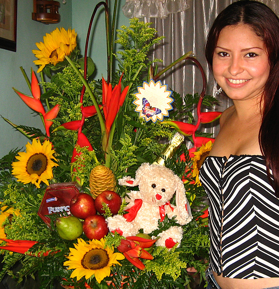 A Colombian woman receiving beautiful flowers, fruits, chocolate, teddy bear and wine as a gift