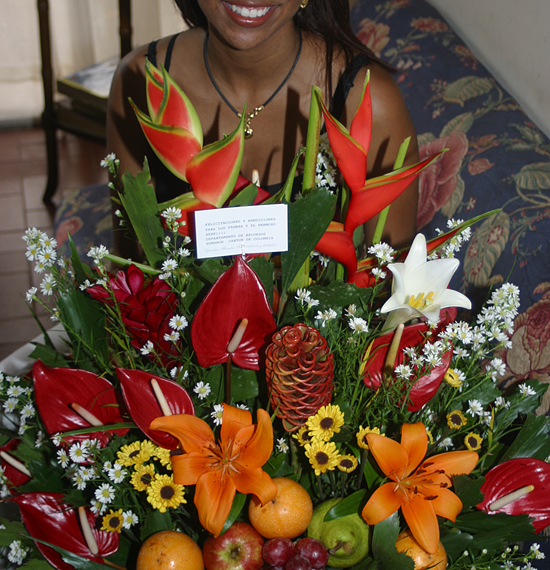 A Colombian woman receiving beautiful flowers, fruits, chocolate, teddy bear and wine as a gift