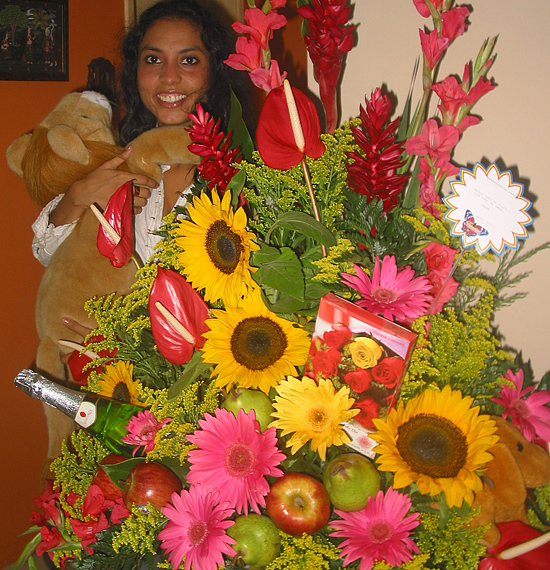 A Colombian woman receiving beautiful flowers, fruits, chocolate, teddy bear and wine as a gift