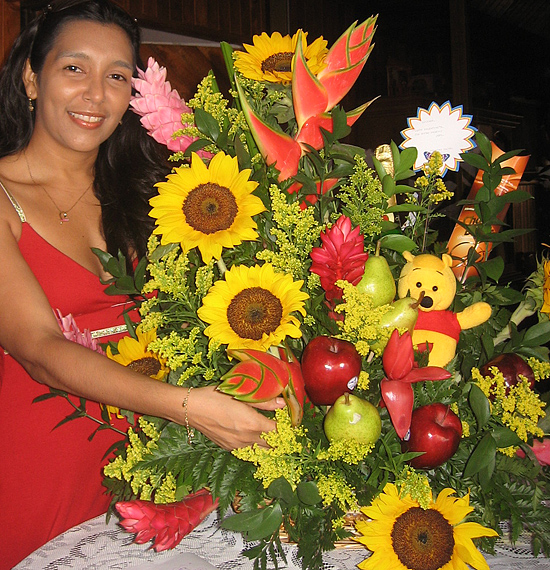 A Colombian woman receiving beautiful flowers, fruits, chocolate, teddy bear and wine as a gift