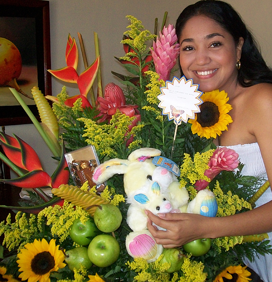 A Colombian woman receiving beautiful flowers, fruits, chocolate, teddy bear and wine as a gift