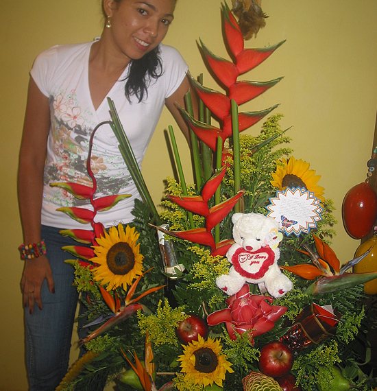 A Colombian woman receiving beautiful flowers, fruits, chocolate, teddy bear and wine as a gift