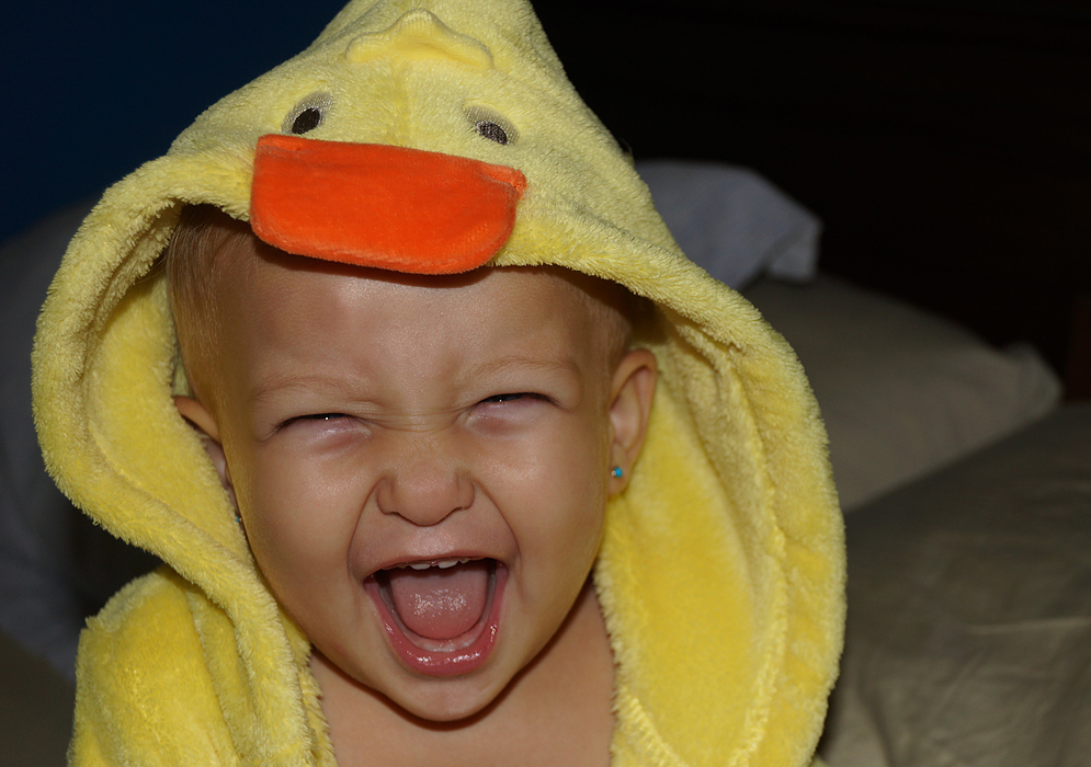 Very happy American Colombian baby with mouth wide open while wearing a yellow duck robe