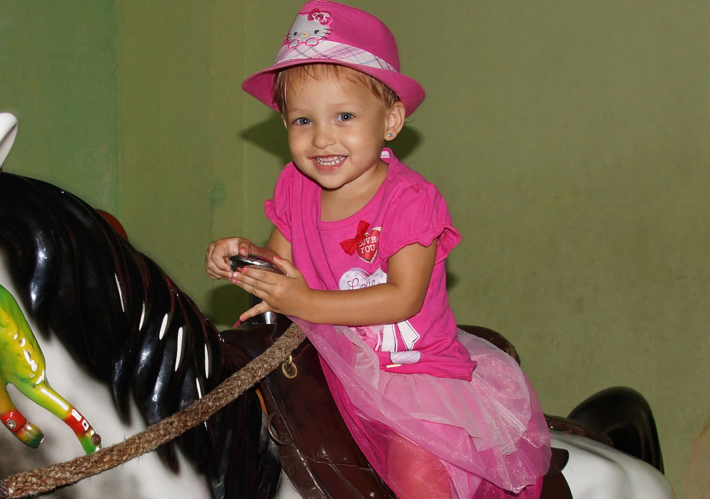 Dressed all in pink a little princess rides a mechanical horse