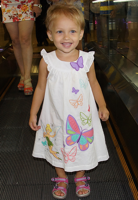 Toddler standing with smiles in her white butterfly dress