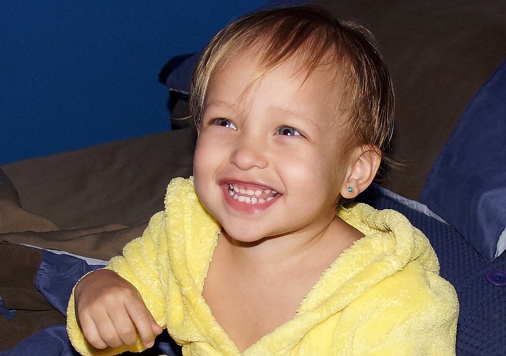 Beautiful and happy Colombian American toddler wearing a yellow robe looks up