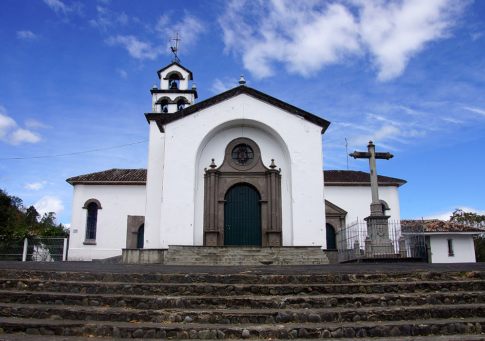 A white church with a stone steps entrance under blue sky