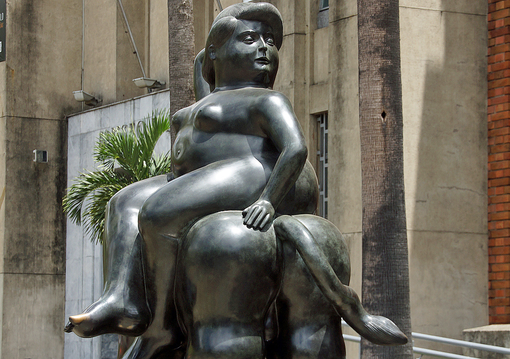 A naked fat woman sitting side-saddle on a bull