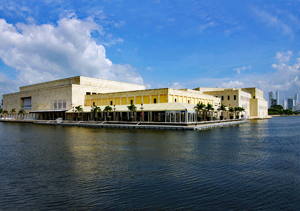 The yellow and tan Convention center with the sea in the foreground