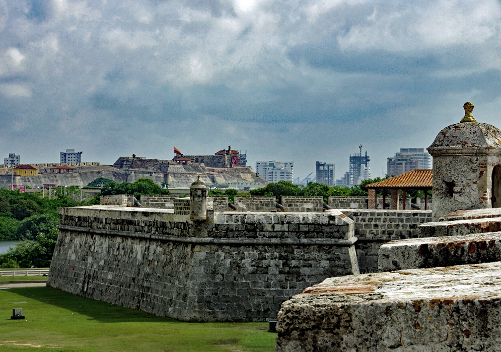 Two historical forts with modern buildings in the background