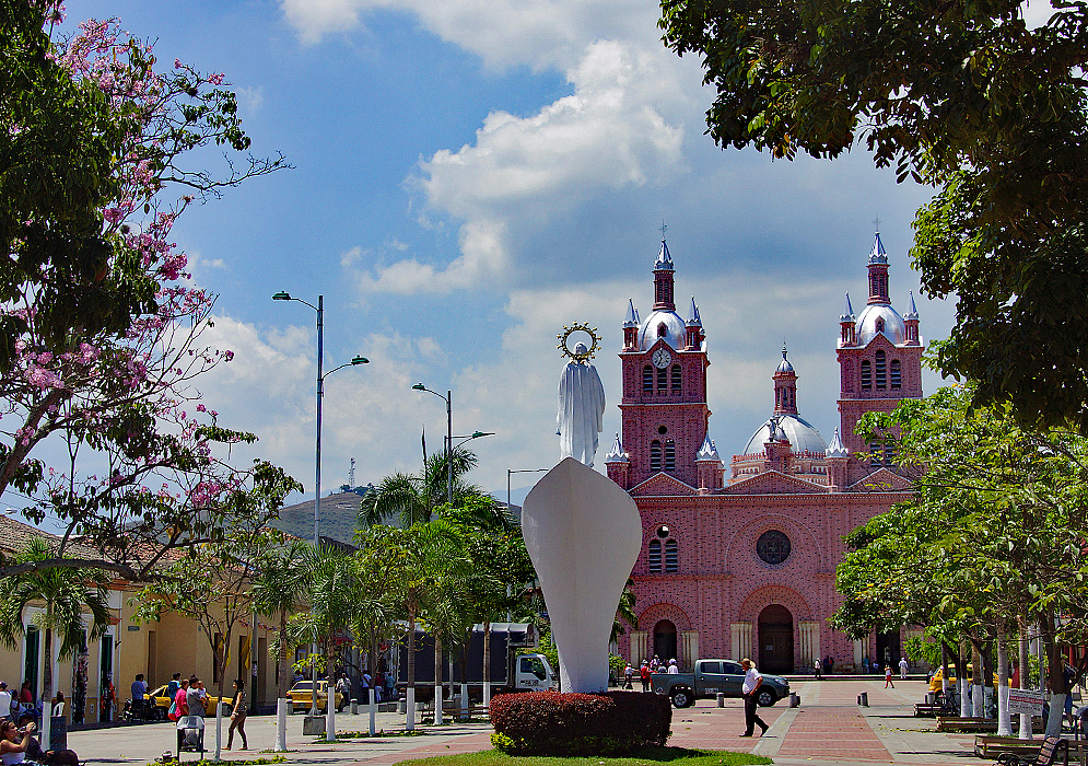 Pink cathedral with white a statue of Jesus in front of the church