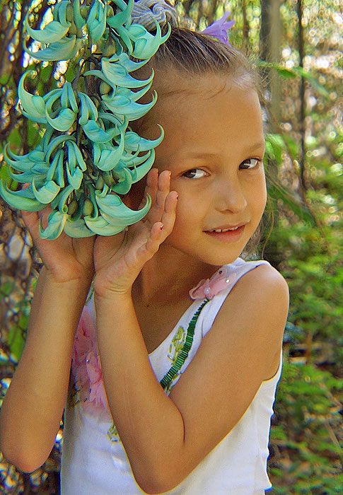 A gorgeous little girl cupping hanging turquoise flowers