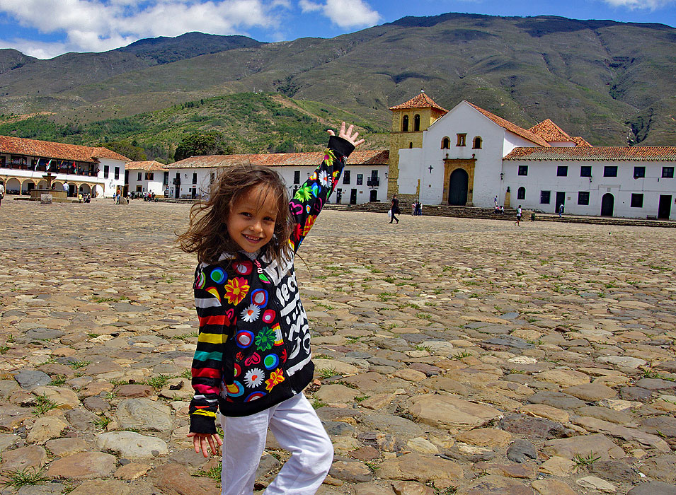 With arms spread-out a pretty girls presents the larges plaza in Colombia