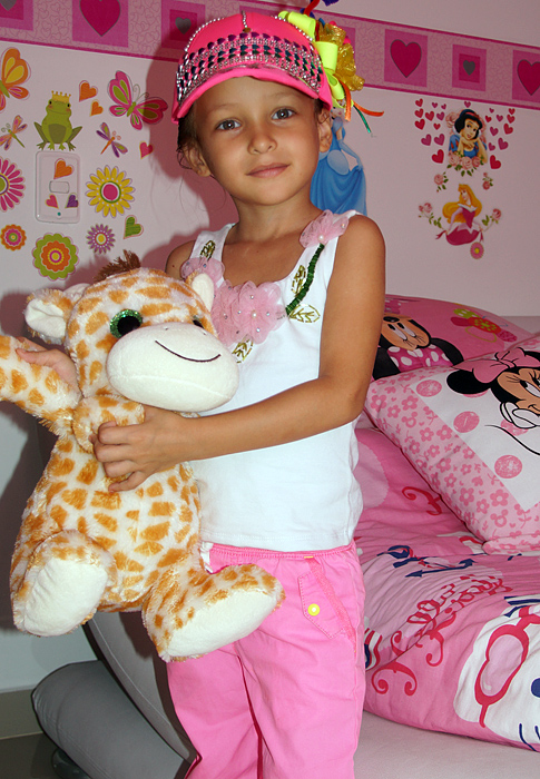 Little girl holding a stuff animal in her bedroom
