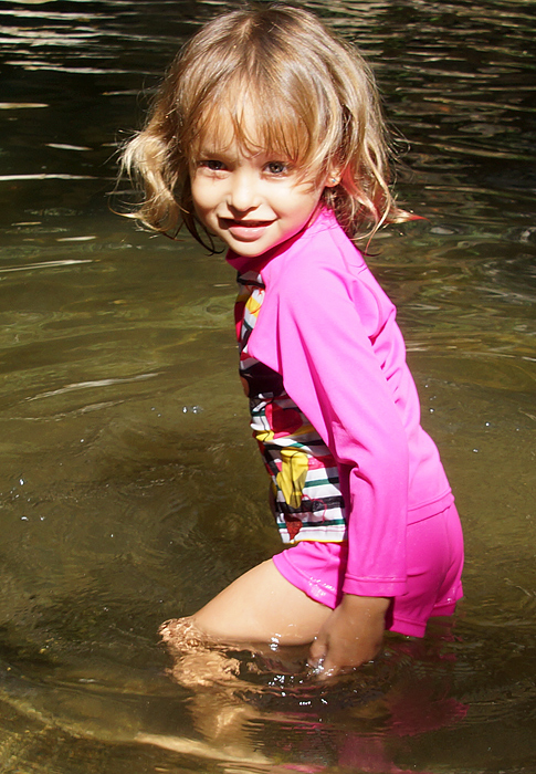 Little girl entering a cold river