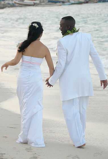 Sweethearts walking hand in hand on the beach after their wedding