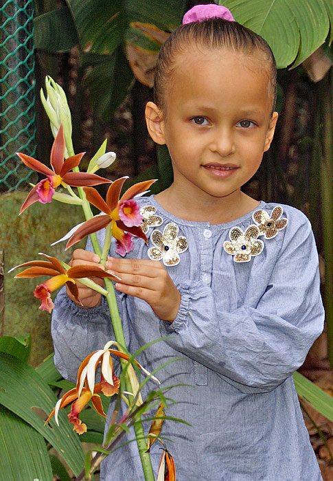 Handsome little girl holding a stalk of orchid flowers