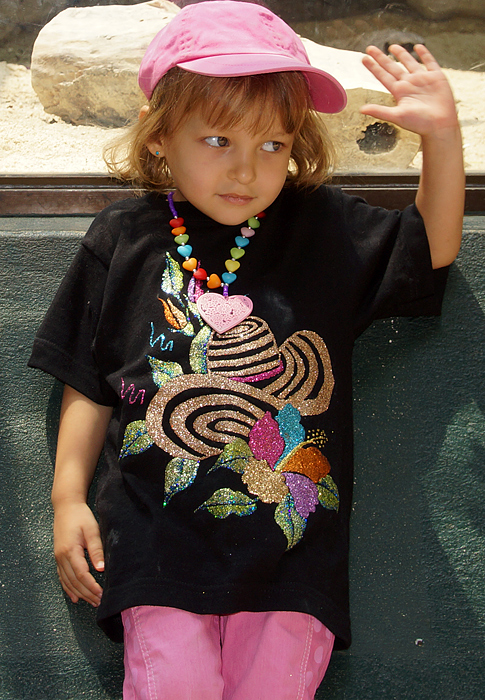 Niña colombo americana con camiseta negra, pantalones y gorro rosados, y un collar