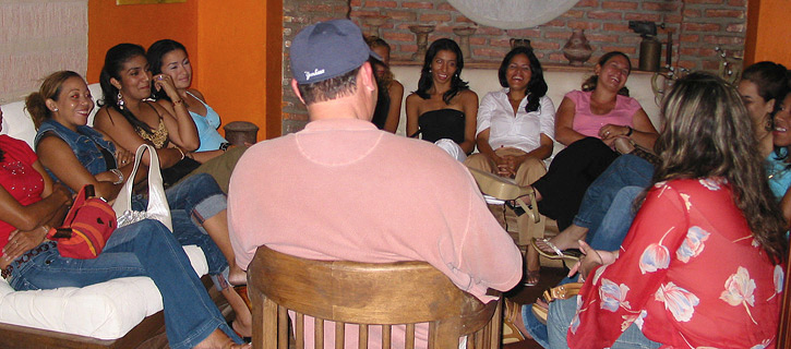 Man chatting with a circle of Colombian women during a casual lounge mixer