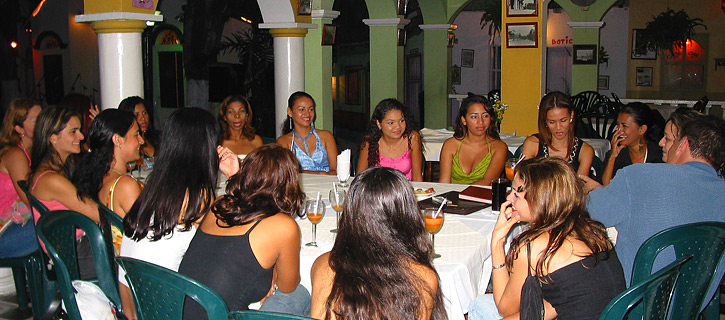 Man surrounded by Colombian women at an evening group introduction event