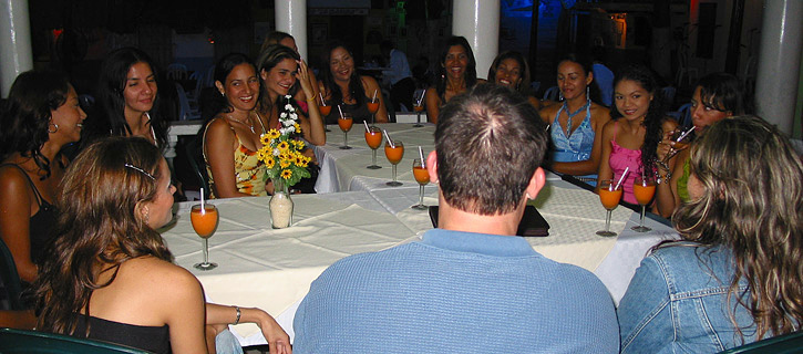Man at a round table with Colombian women enjoying drinks during a matchmaking dinner