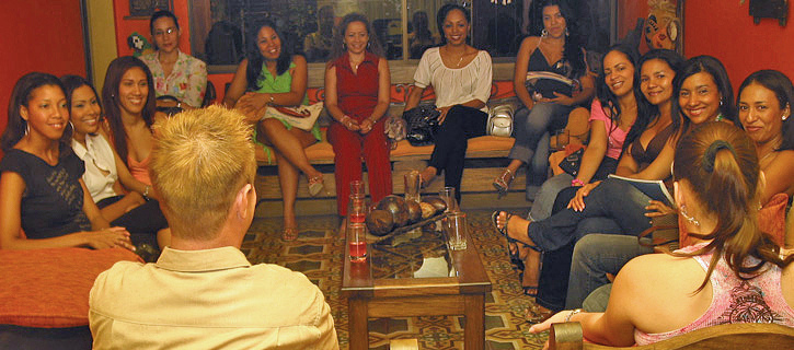 A group of Colombian women in a living room meeting a very happy man