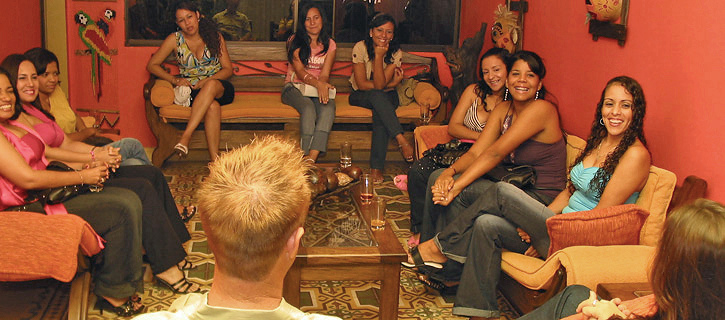 Circle of Colombian women smiling during a living-room social with a guest
