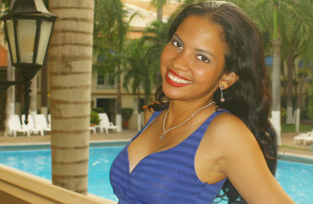 A beautiful Latin wife with a big smile on a balcony above a pool