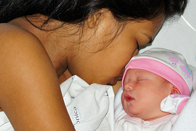 Colombia mom and new American Colombian born baby sleeping close together for the first time at the hospital bed