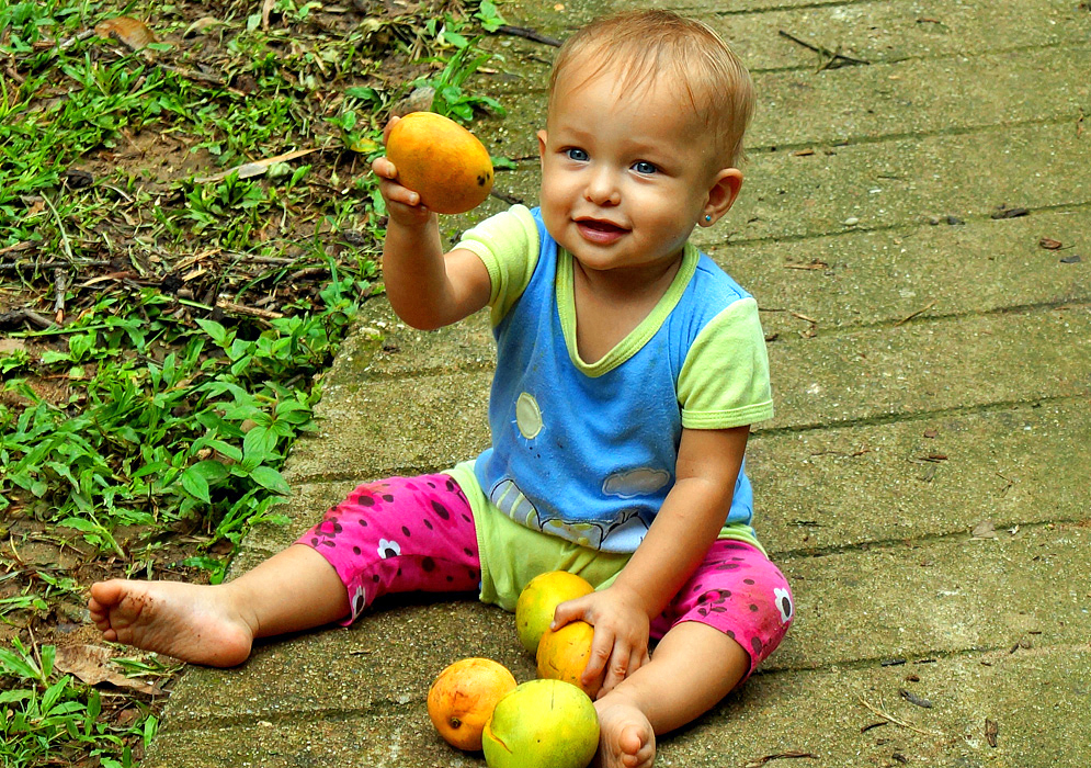 Mango and Beautiful Girl Beautiful smiling one year old girl holding up a mango