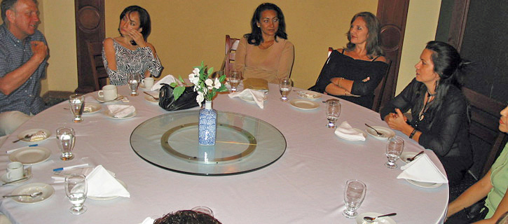 A group of women sitting on sofas in a relaxed lounge smiling and laughing during a social introduction event with a man