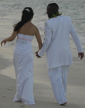 Pareja casada caminando por la playa de la mano