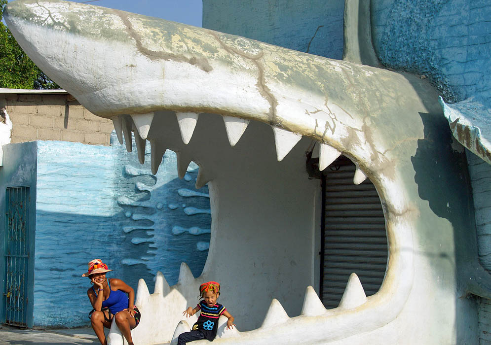 A Colombian mom and daughter sitting in the jaws of a large ceramic shark