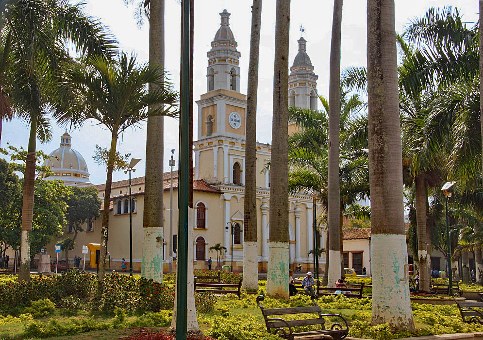 San Laureano Church A tan-color church with two towers behind a park with palm trees