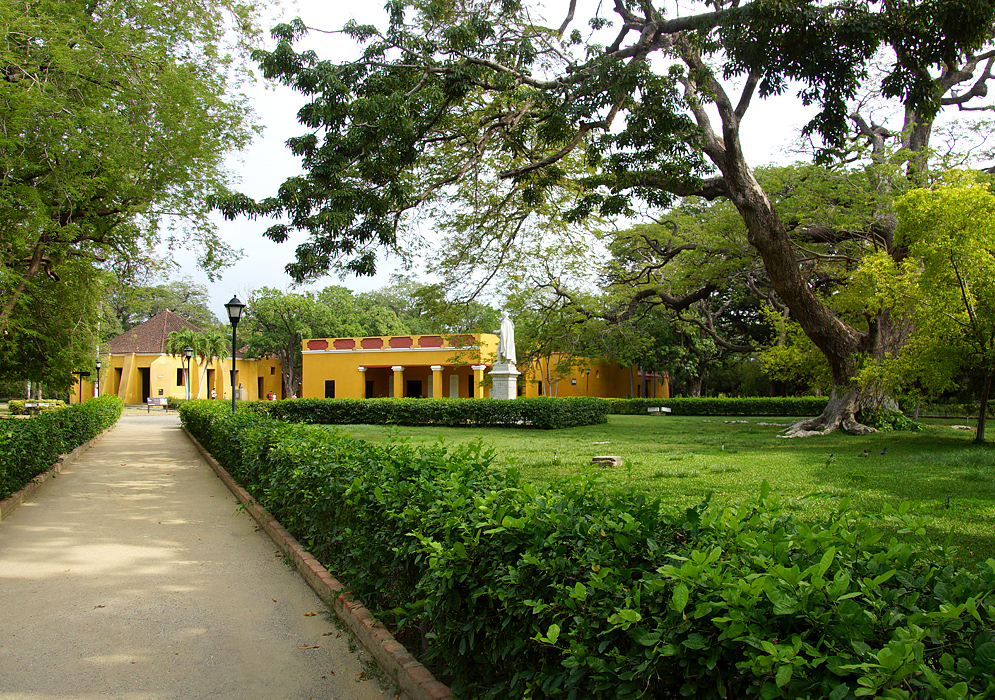 A walkway leading to yellow buildings and a statue