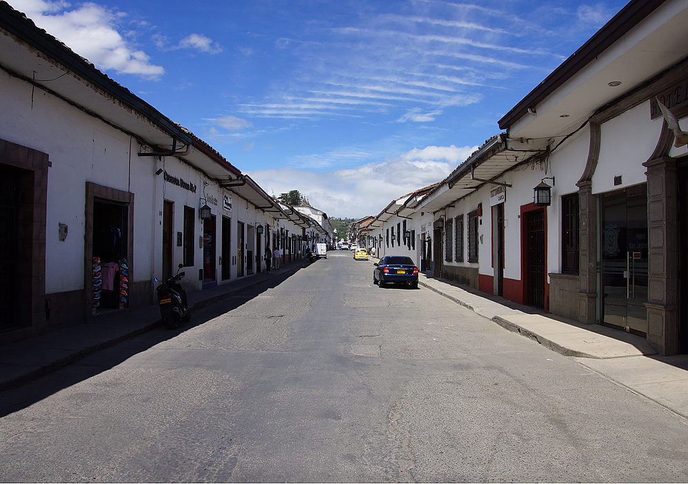A street in-between small white building 